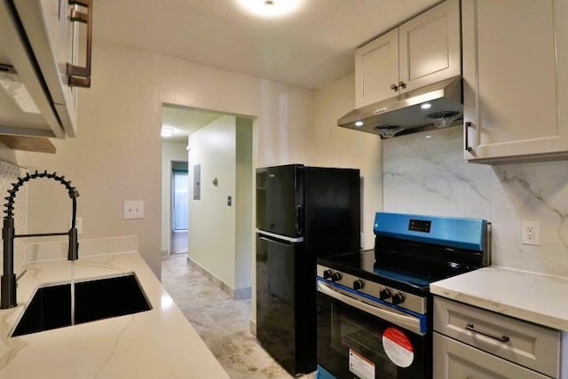 kitchen with sink, stainless steel range with electric cooktop, decorative backsplash, black fridge, and light stone countertops