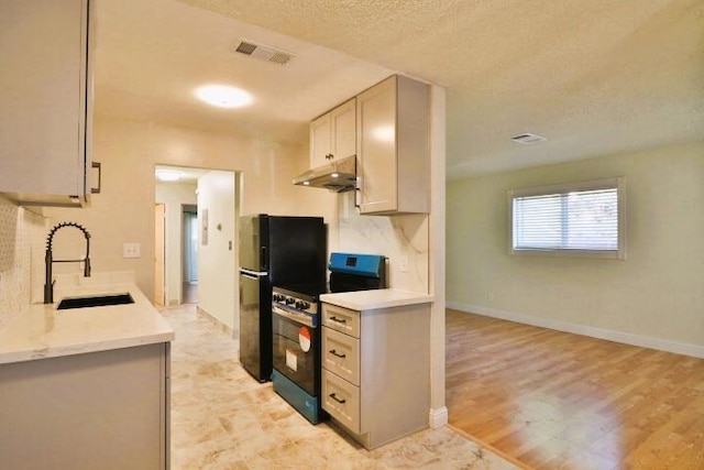 kitchen featuring light hardwood / wood-style floors, sink, stainless steel electric range, and a textured ceiling