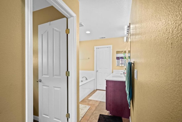 bathroom with tile patterned flooring, vanity, and a tub to relax in