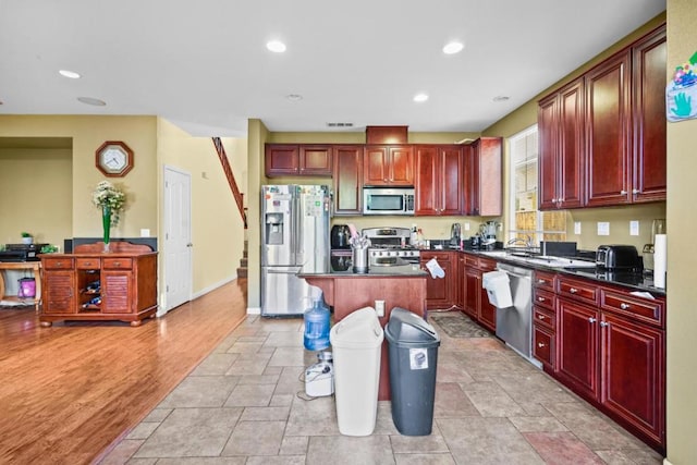 kitchen featuring a breakfast bar, stainless steel appliances, a kitchen island, and light hardwood / wood-style flooring