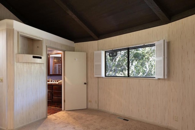 carpeted empty room with beam ceiling