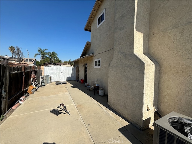 view of side of home featuring a storage shed, a patio area, and central AC unit