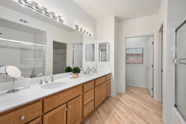 bathroom with wood-type flooring, a shower with door, and vanity