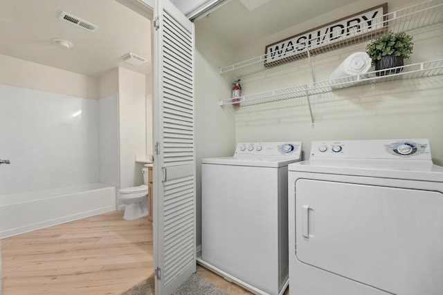 laundry area with independent washer and dryer and light wood-type flooring