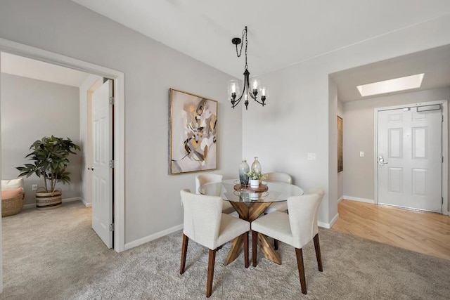 dining area with light carpet, an inviting chandelier, and a skylight