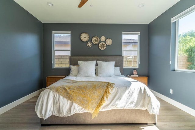 bedroom with hardwood / wood-style floors, ceiling fan, and multiple windows