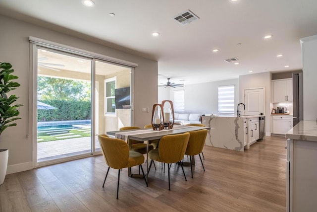 dining space with light wood-type flooring, ceiling fan, and sink