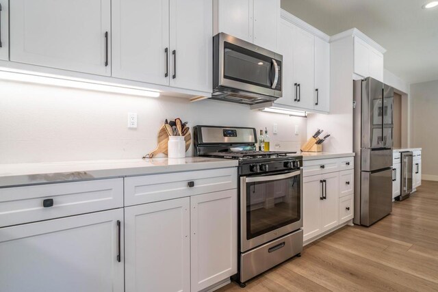 kitchen with wine cooler, white cabinetry, light hardwood / wood-style flooring, and appliances with stainless steel finishes