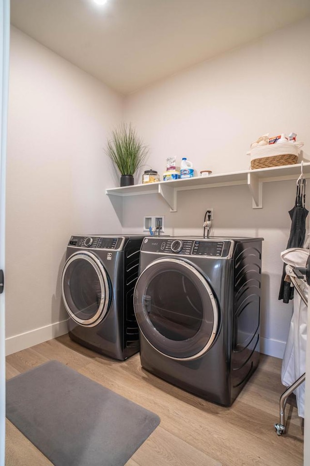 clothes washing area featuring light wood-type flooring and separate washer and dryer