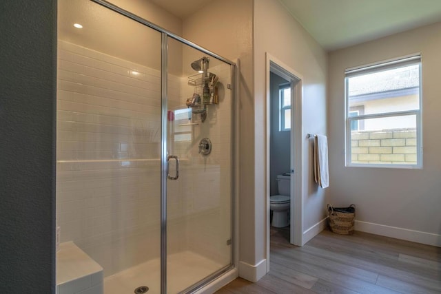 bathroom with hardwood / wood-style floors, a shower with door, and toilet