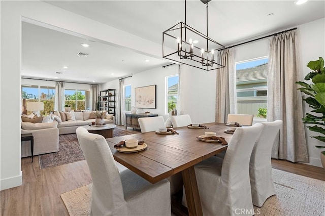 dining area featuring a wealth of natural light, light hardwood / wood-style flooring, and an inviting chandelier