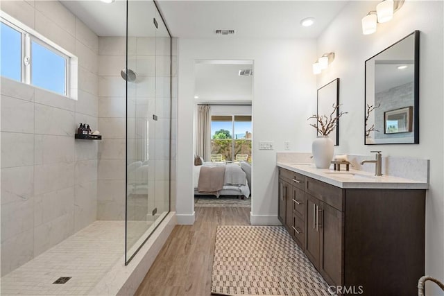 bathroom with wood-type flooring, vanity, a tile shower, and plenty of natural light