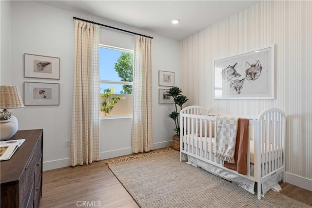 bedroom with a nursery area and hardwood / wood-style flooring