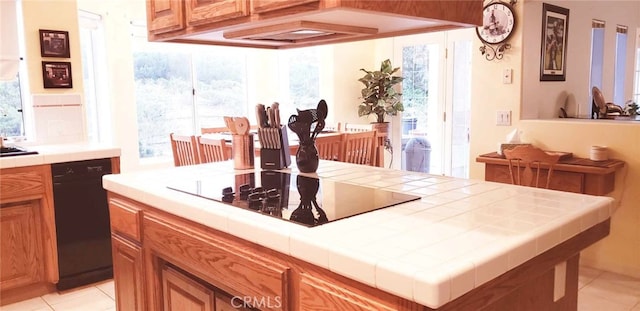 kitchen with black appliances, tile counters, light tile patterned floors, and a wealth of natural light