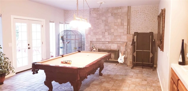 recreation room with a tiled fireplace, french doors, and pool table