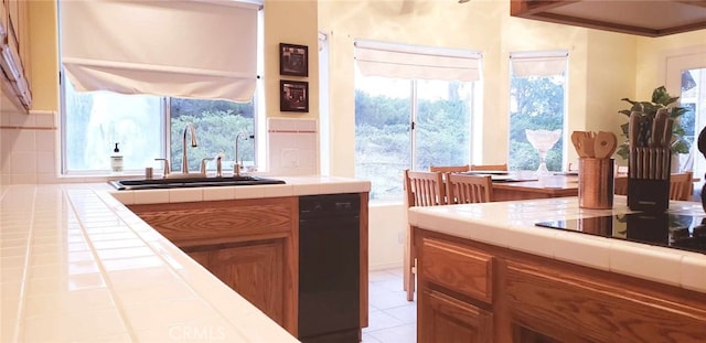 kitchen featuring backsplash, tile counters, black appliances, and sink