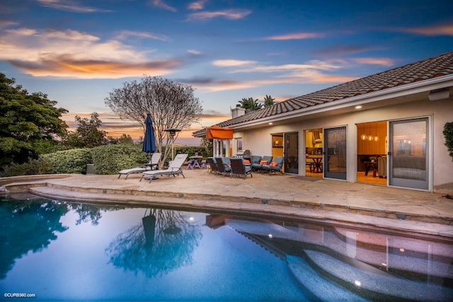 pool at dusk with a patio area