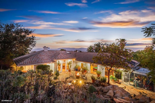 back house at dusk with a patio and a mountain view