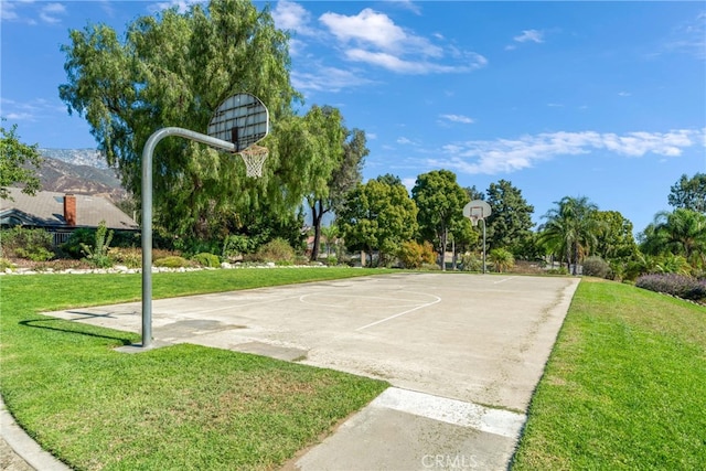 view of sport court with a mountain view and a lawn