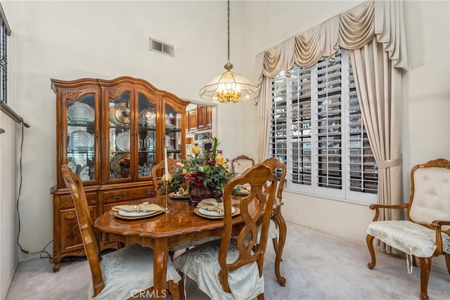 dining space with light carpet and an inviting chandelier