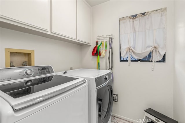 clothes washing area featuring cabinets, washer and dryer, and light tile patterned floors