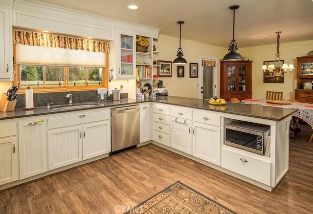 kitchen with decorative light fixtures, a sink, a chandelier, light wood finished floors, and stainless steel appliances