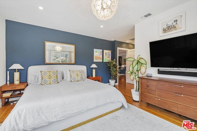 bedroom featuring wood-type flooring and an inviting chandelier