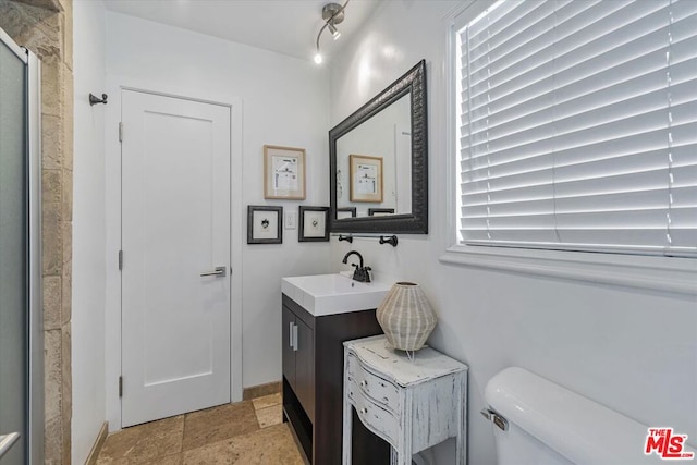 bathroom featuring vanity, toilet, and a shower with door