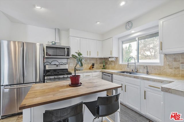 kitchen with a center island, sink, appliances with stainless steel finishes, butcher block countertops, and white cabinetry