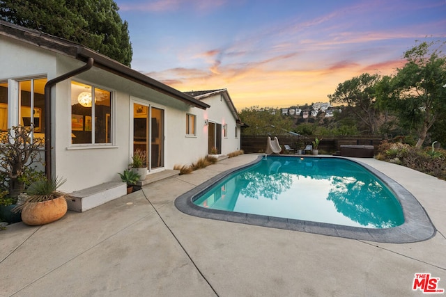 pool at dusk featuring a patio area