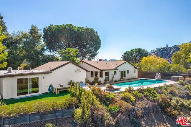 rear view of property featuring a fenced in pool