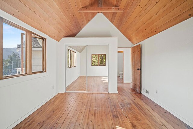 unfurnished bedroom featuring light hardwood / wood-style floors, lofted ceiling with beams, and wood ceiling