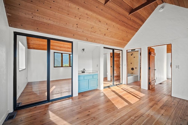 interior space featuring vaulted ceiling, wooden ceiling, ensuite bathroom, and sink