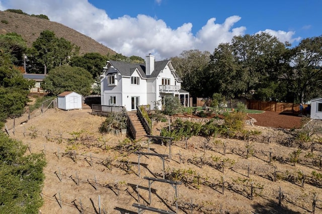 back of house with a balcony, a mountain view, and a storage shed