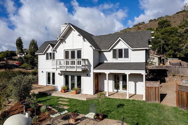 back of house with a balcony, a lawn, french doors, and a patio