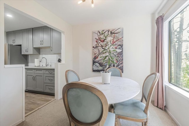 carpeted dining room featuring sink and plenty of natural light