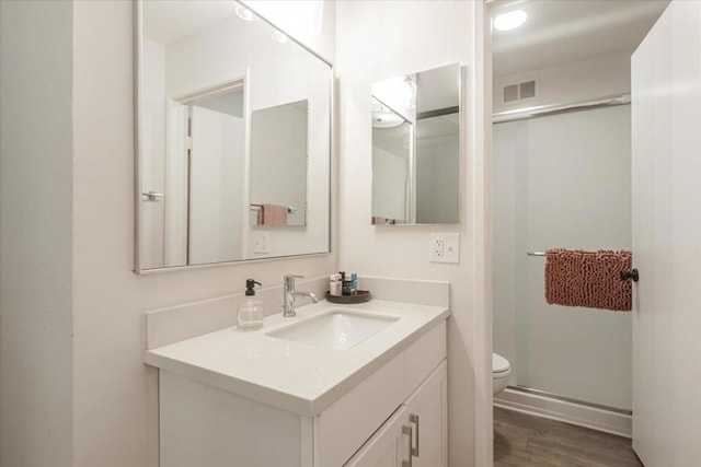 bathroom featuring hardwood / wood-style flooring, vanity, toilet, and a shower with door