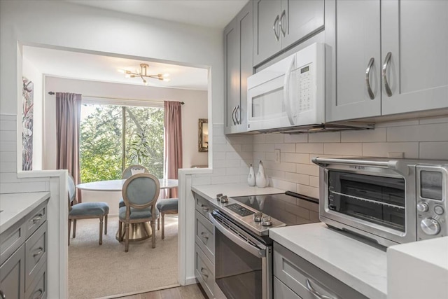 kitchen featuring electric stove, gray cabinets, tasteful backsplash, and light wood-type flooring