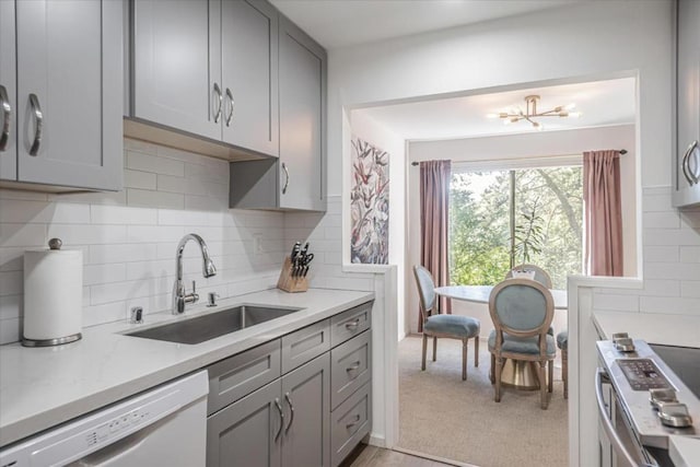 kitchen featuring stainless steel electric stove, dishwasher, sink, gray cabinetry, and backsplash