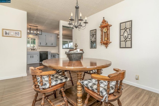 dining room featuring a chandelier, a textured ceiling, light wood-type flooring, and sink