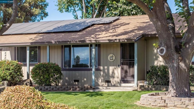 view of front of property featuring a front yard and solar panels