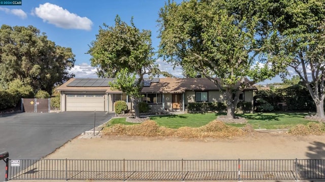 ranch-style house featuring solar panels, a garage, and a front yard