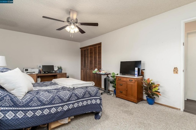 bedroom with ceiling fan, a textured ceiling, light carpet, and a closet