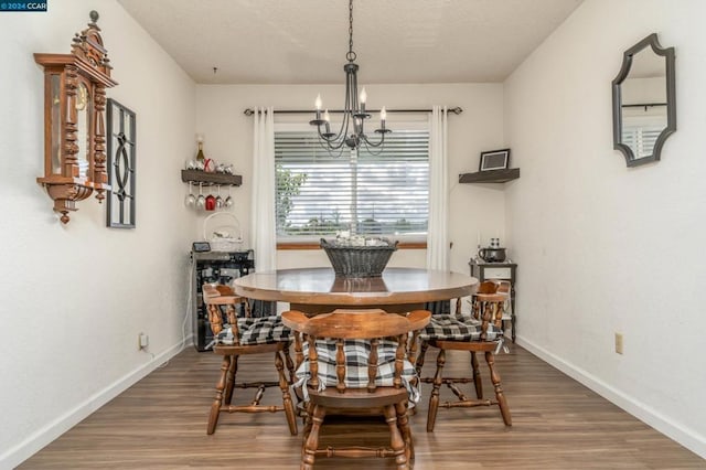 dining space with hardwood / wood-style floors and an inviting chandelier