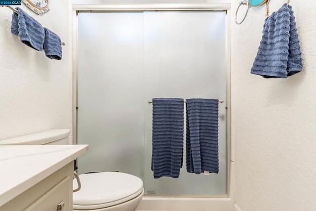 bathroom featuring vanity, toilet, and walk in shower