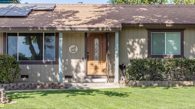 view of exterior entry with a yard and solar panels