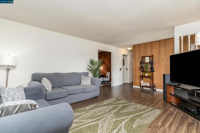 living room featuring dark wood-type flooring and a textured ceiling