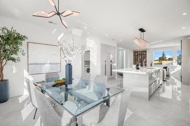 dining area featuring washer / dryer, a notable chandelier, and sink