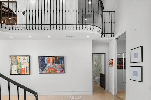 stairway with tile patterned floors and a towering ceiling