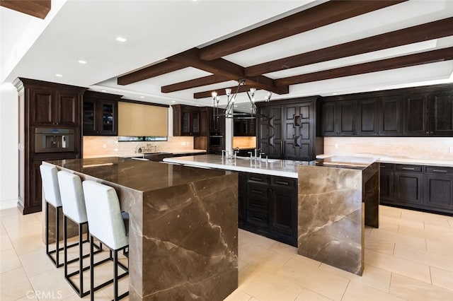 kitchen with beamed ceiling, stainless steel oven, a spacious island, and tasteful backsplash